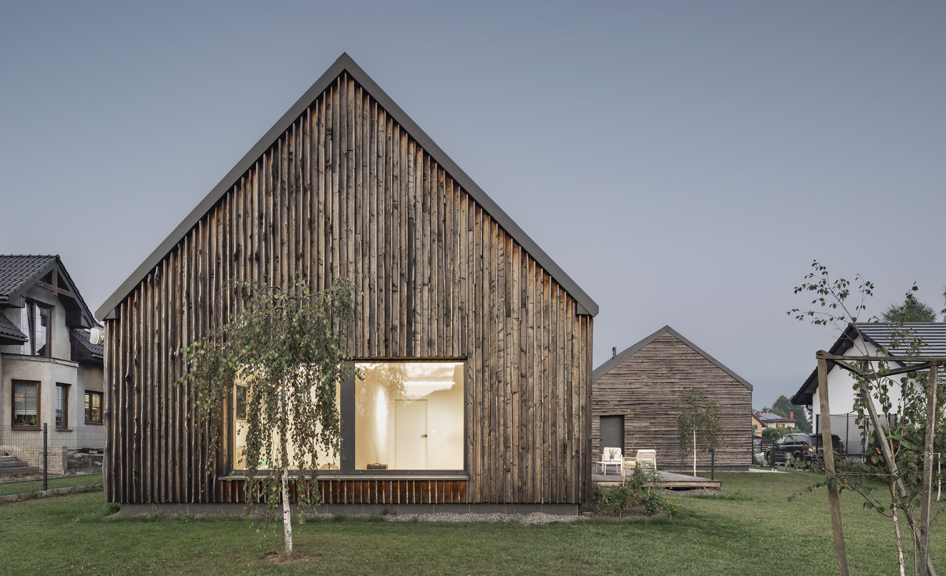 Widok z ogrodu na dom z drewnianą nieheblowaną elewacją projektu