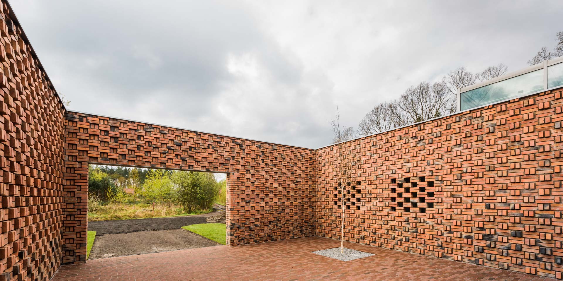 Otwarte wnętrze ogrodzone ceglanym murem z wjazdem dla samochodu