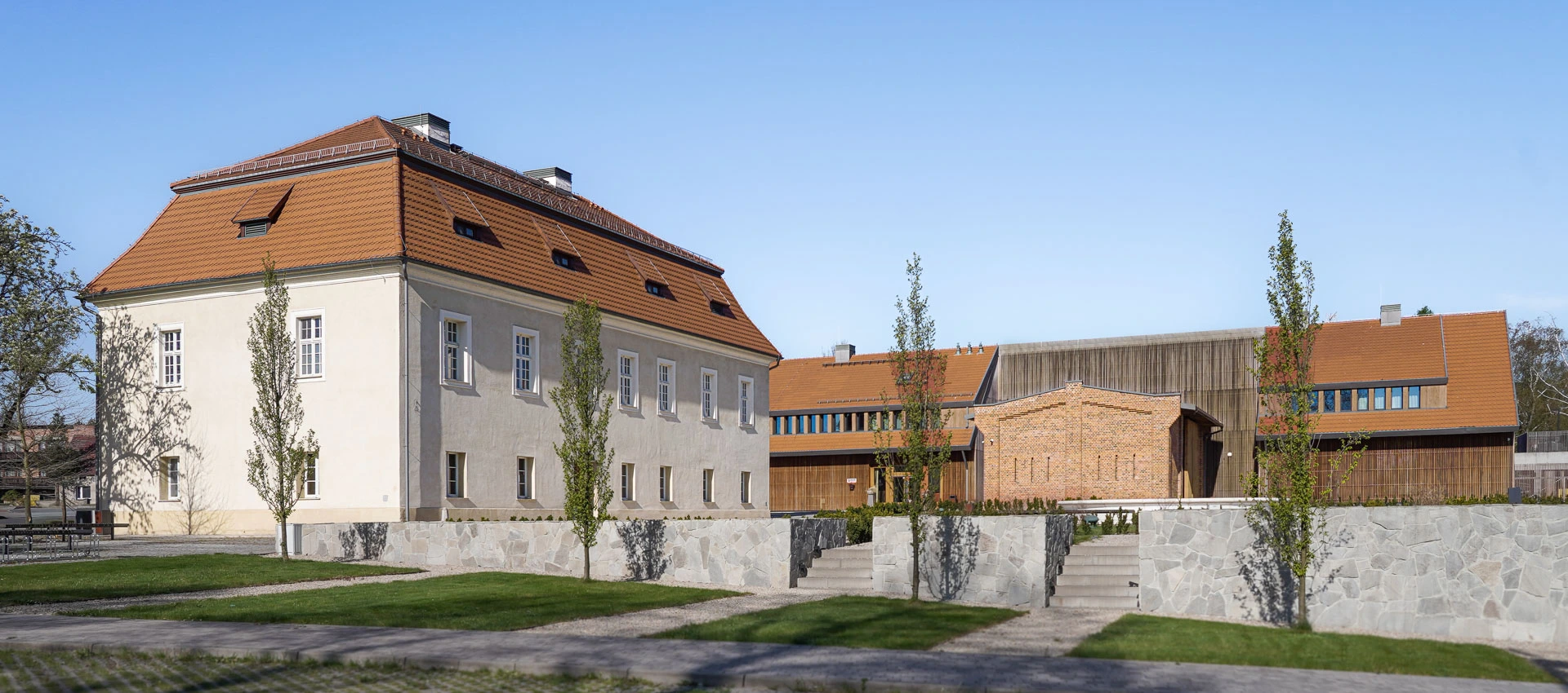 Odnowiony dwór z folwarkiem z czerwoną dachówką i sąsiednią roślinnoscią