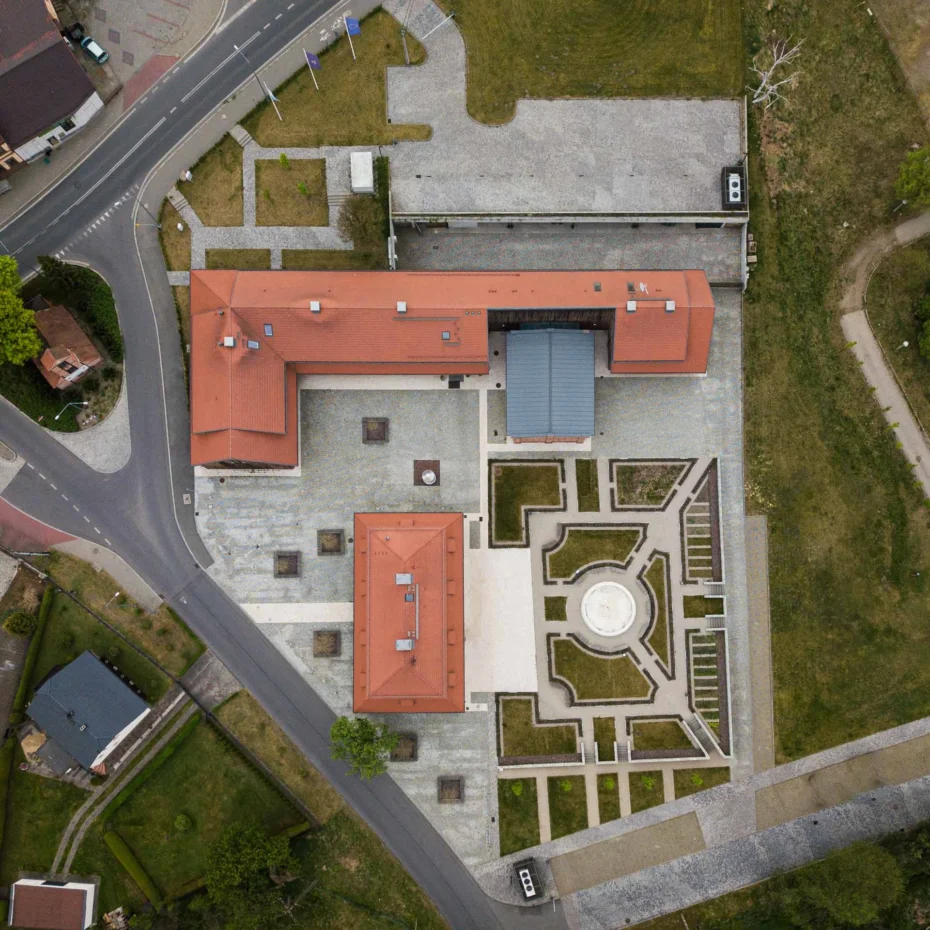 widok z lotu ptaka zabytkowego dworu z dachem z dachówki i towarzyszącą zabudową drewnianą