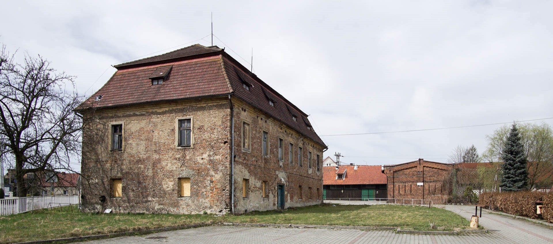Zaniedbany dwór cysterski z folwarkiem zbudowany z cegły