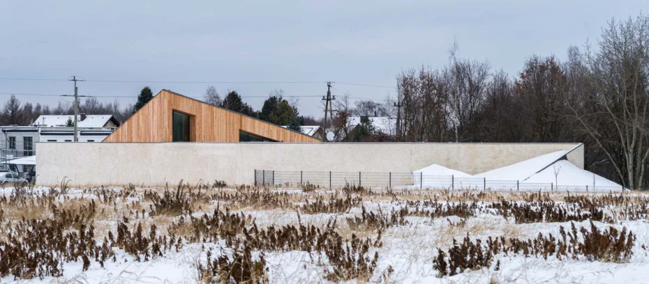 Single family house with bright facade in winter aura with woods in the background