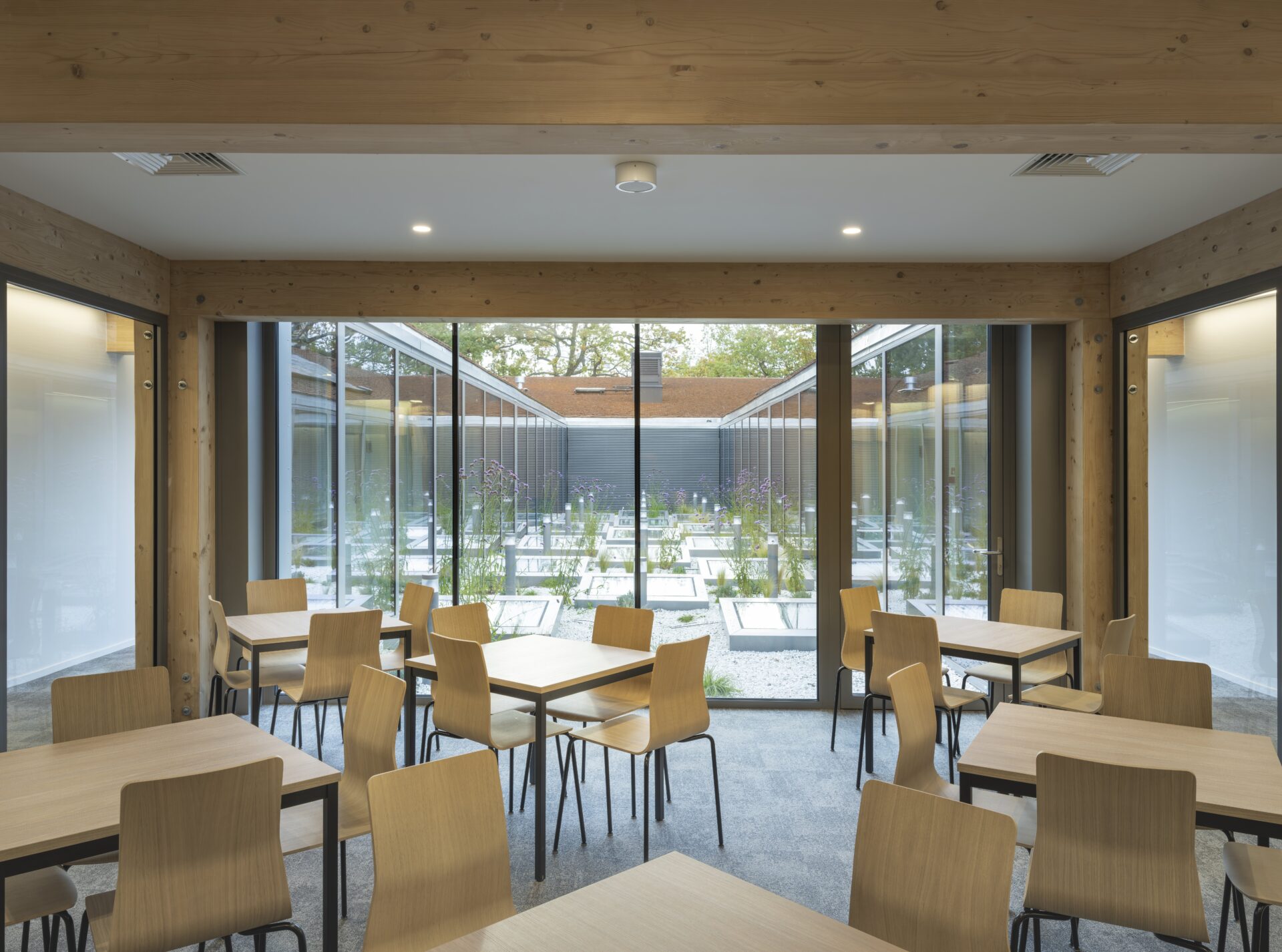 Przeszklona część wspólna z krzesłami i stołami w budynku użyteczności publicznej