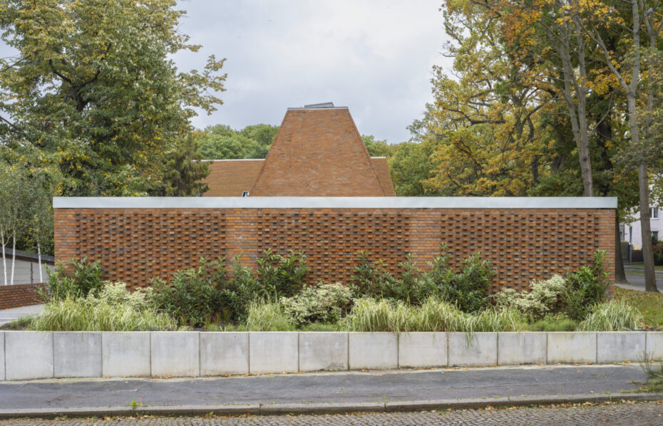 Półpubliczny ogród budynku publicznego na tle ceglanego ogrodzenia i elewacji