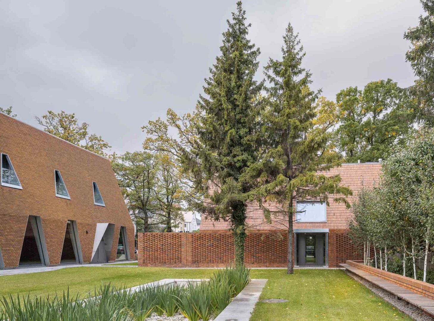 Ogólnodostępny ogród z trawnikiem i drzewami przy budynku ośrodka szkoleniowego