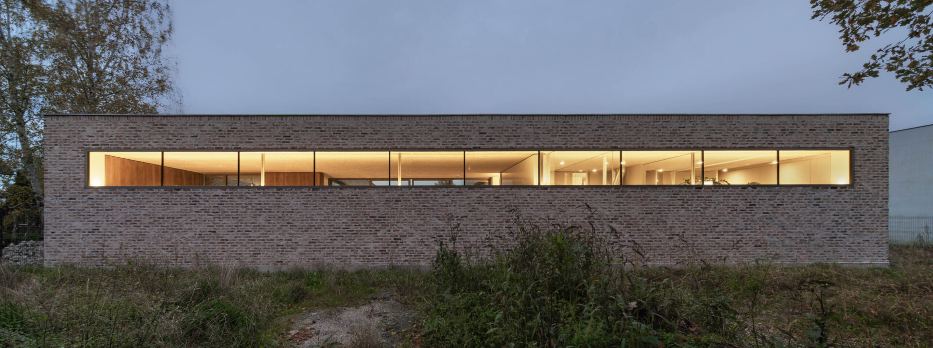 Ceglana elewacja domu jednorodzinnego po zmroku z rozświetlonym wnętrzem