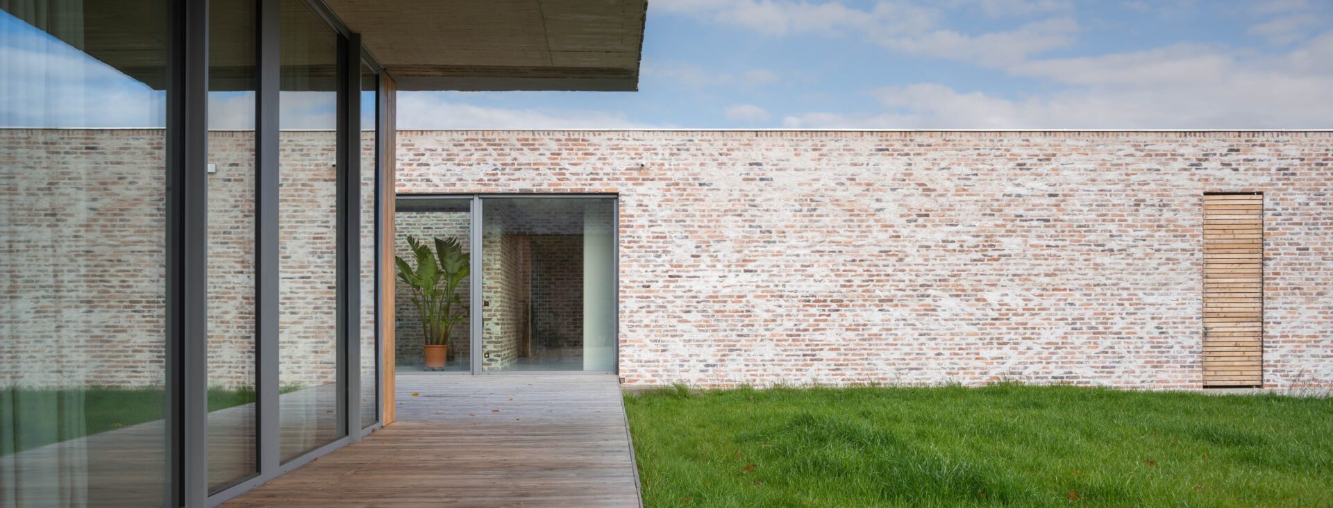 Widok z tarasu na ceglaną elewacje domu jednorodzinnego