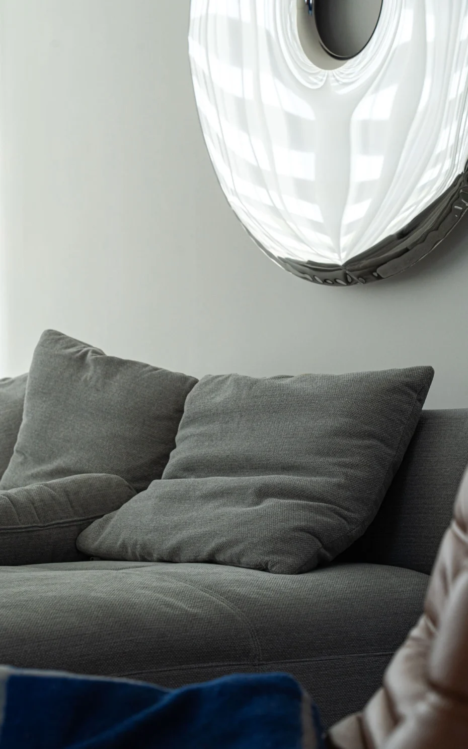 Szara sofa z widoczną teksturą i okrągłą dekoracją na ścianie